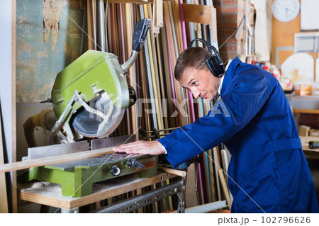 Man operating circular saw in wood workshop Man operating circular saw in wood workshop 102796626