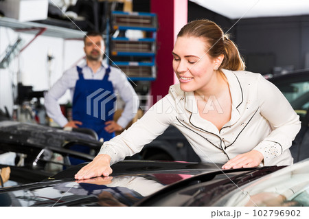 Happy woman touching surface of repainted car Happy woman touching surface of repainted car 102796902