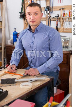 young male carpenter working wood plank at workshop young male carpenter working wood plank at workshop 102796911