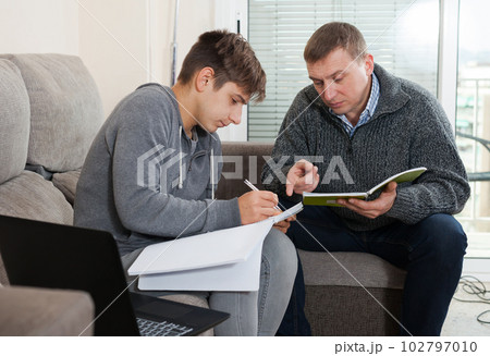 Father helping son to do homework 102797010