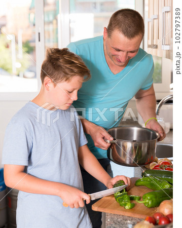 Boy and his father are cooking soup together in the kitchen 102797389