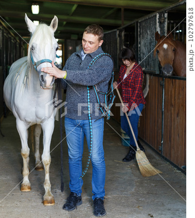 Man in casual clothes who works at stable Man in casual clothes who works at stable 102797618