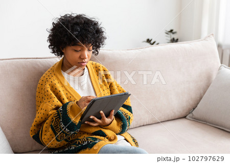 African american girl holding digital tablet touch screen typing scroll page at home. Woman with mobile tech device surfing internet using social media apps playing game. Study work shopping online African american girl holding digital tablet touch screen typing scroll page at home. Woman with mobile tech device surfing internet using social media apps playing game. Study work shopping online 102797629