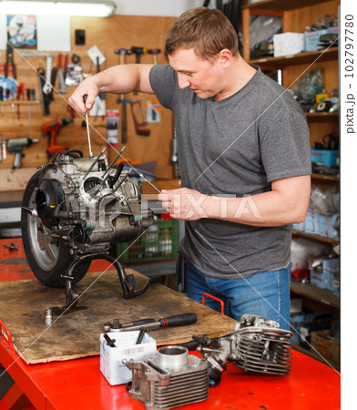 Man is repairing modern moto and looking on detail for it Man is repairing modern moto and looking on detail for it 102797780