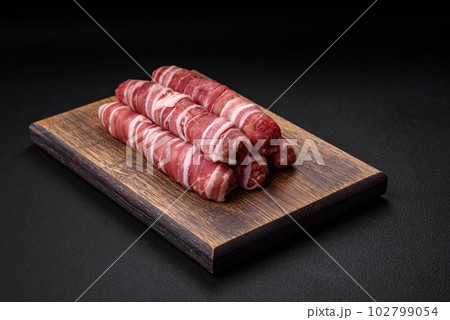 Raw minced meat wrapped in bacon with salt and spices or cevapcici Raw minced meat wrapped in bacon with salt and spices or cevapcici 102799054
