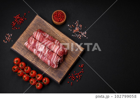 Raw minced meat wrapped in bacon with salt and spices or cevapcici Raw minced meat wrapped in bacon with salt and spices or cevapcici 102799058