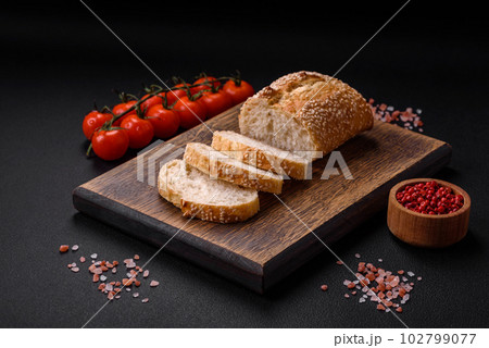 Crispy wheat flour baguette with sesame seeds on a wooden cutting board 102799077