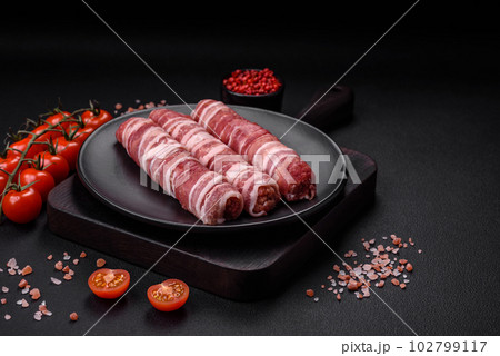 Raw minced meat wrapped in bacon with salt and spices or cevapcici Raw minced meat wrapped in bacon with salt and spices or cevapcici 102799117
