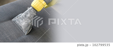 Banner Man holding modern washing vacuum cleaner and cleaning dirty sofa with professionally detergent copy space. Professional spring clean at home concept 102799535