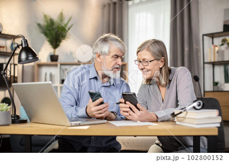 Spouses checking social media via phone during break at home Spouses checking social media via phone during break at home 102800152