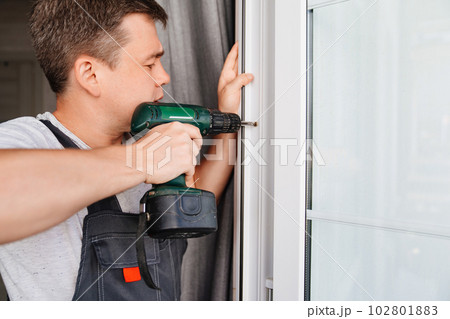 A repairman repairs or adjusts window frames or glass doors on the terrace. 102801883