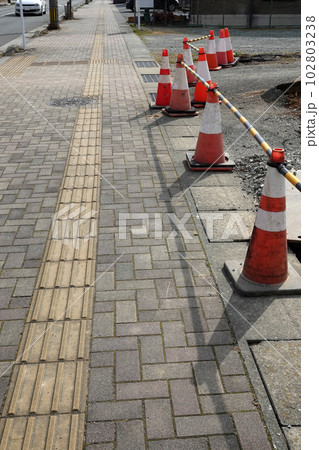 歩道横側溝に並べられた工事保安用の赤と白のロードコーン 歩道横側溝に並べられた工事保安用の赤と白のロードコーン 102803238
