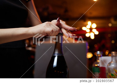 Open the champagne. A woman's hand in the foreground, uncorking a bottle of Prosecco. 102803567