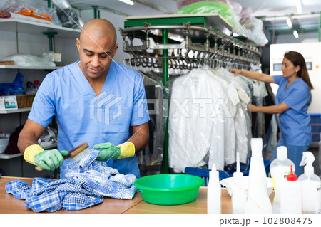Focused man drycleaner removing spots and stains 102808475
