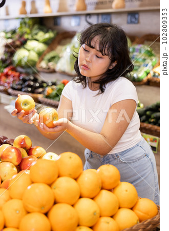 Attentive young woman purchaser choosing apples in grocery store Attentive young woman purchaser choosing apples in grocery store 102809353