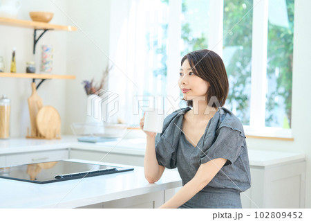 ダイニングキッチンでコーヒーを飲む若い女性 ダイニングキッチンでコーヒーを飲む若い女性 102809452
