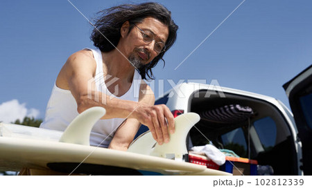 サーフボードにフィンを取り付ける男性 102812339