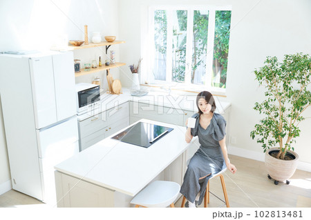 ダイニングキッチンでコーヒーを飲む若い女性 102813481