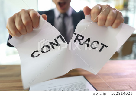 Irritated man tears contract paper apart sitting at table Irritated man tears contract paper apart sitting at table 102814029