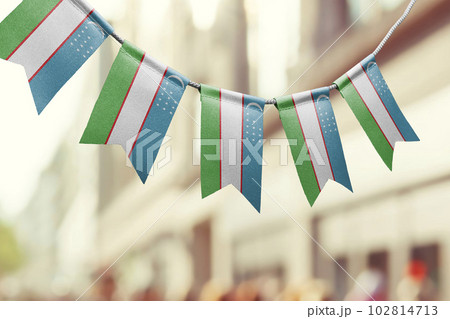A garland of Uzbekistan national flags on an abstract blurred background A garland of Uzbekistan national flags on an abstract blurred background 102814713
