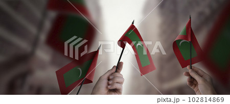 A group of people holding small flags of the Maldives in their hands A group of people holding small flags of the Maldives in their hands 102814869