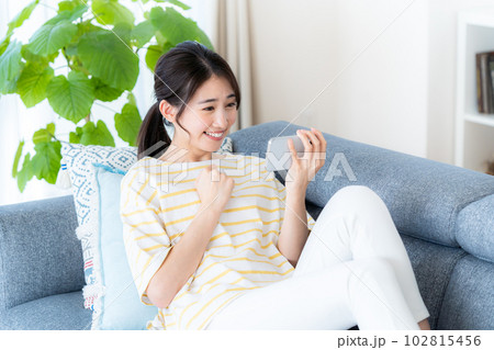 部屋でスマホを操作する若い女性 102815456