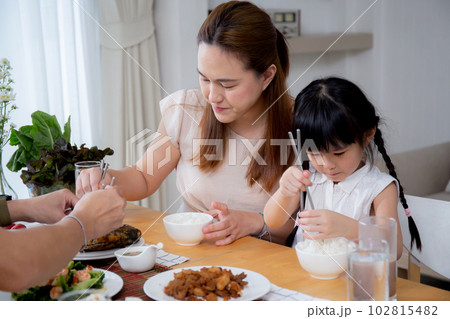 Happiness asian family mother and father and daughter eating food in kitchen together. 102815482