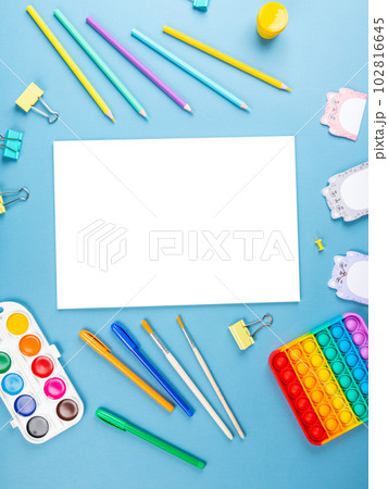 Top view arrangement album with white sheets and pens, pencils, paper clips and other office supplies on blue background Top view arrangement album with white sheets and pens, pencils, paper clips and other office supplies on blue background 102816645