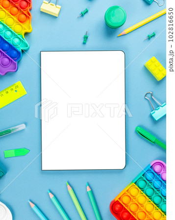 Top view arrangement album with white sheets and pens, pencils, paper clips and other office supplies on blue background Top view arrangement album with white sheets and pens, pencils, paper clips and other office supplies on blue background 102816650