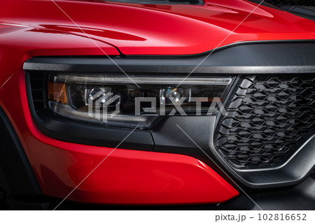 Red car headlights. Exterior detail. Close up detail on one of the LED headlights modern car. 102816652