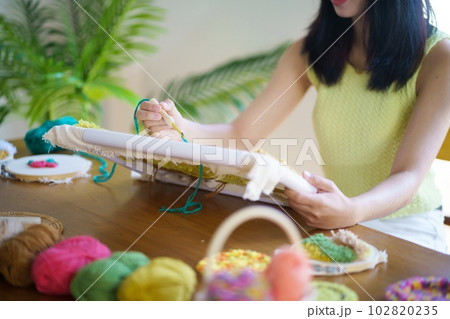 Punch needle. Asian Woman making handmade Hobby knitting in studio workshop. designer workplace Handmade craft project DIY embroidery concept. 102820235