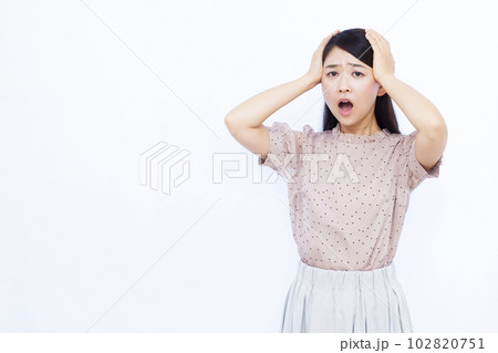 白い背景の前で頭を抱えて驚く30代の女性 白い背景の前で頭を抱えて驚く30代の女性 102820751