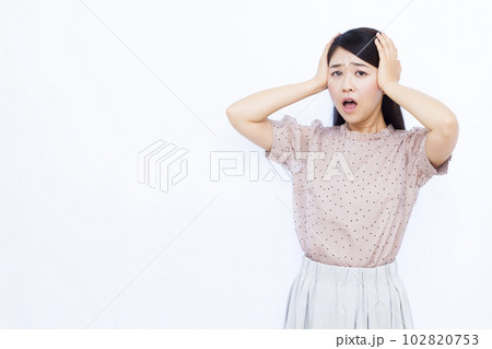 白い背景の前で頭を抱えて驚く30代の女性 白い背景の前で頭を抱えて驚く30代の女性 102820753