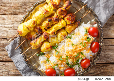 Persian Jujeh kabab is an Iranian dish that consists of grilled chunks of chicken marinated in saffron and yogurt served with rice closeup on the plate. Horizontal top view 102821266