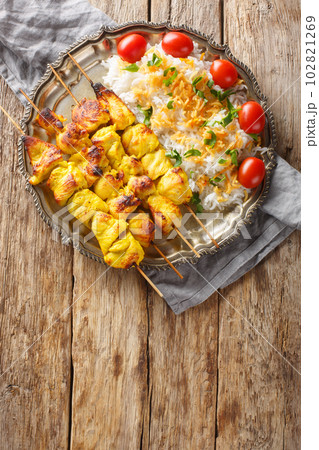 Grilled chicken kebab is known as jujeh kabab with rice closeup on the plate. Vertical top view 102821269