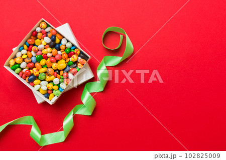 Set of different sweet candy in a paper box with a satin ribbon on a colored background. Holiday concept Set of different sweet candy in a paper box with a satin ribbon on a colored background. Holiday concept 102825009