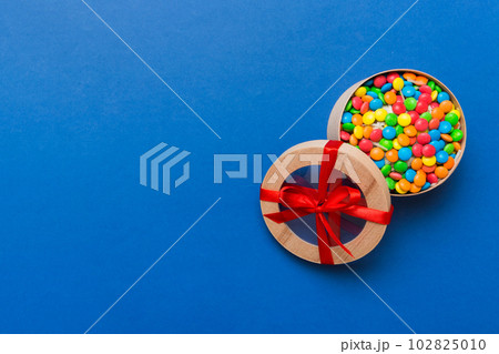 Set of different sweet candy in a paper box with a satin ribbon on a colored background. Holiday concept Set of different sweet candy in a paper box with a satin ribbon on a colored background. Holiday concept 102825010