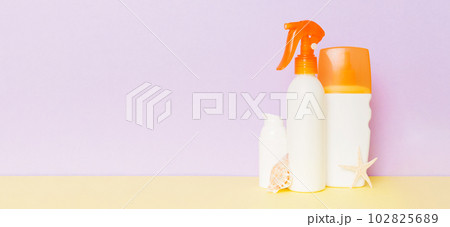 Beach accessories. Moisturiser sunscreen suntan lotion bottle for UVB skincare protection in summer with seashells on colored background. Mock up with copy space Beach accessories. Moisturiser sunscreen suntan lotion bottle for UVB skincare protection in summer with seashells on colored background. Mock up with copy space 102825689