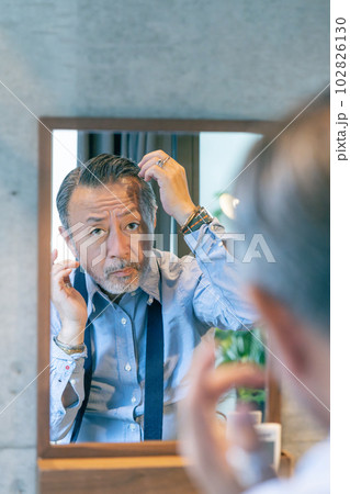 鏡を見て髪の毛を整えるミドルエイジの男性　縦位置 102826130