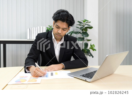 Young asian businessman in white shirt and black suit working with multicolor chart. Young asian businessman in white shirt and black suit working with multicolor chart. 102826245