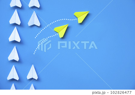 Two Yellow paper airplanes origami leaving other white airplanes on blue background with customizable space for text or ideas. Leadership skills concept and copy space Two Yellow paper airplanes origami leaving other white airplanes on blue background with customizable space for text or ideas. Leadership skills concept and copy space 102826477