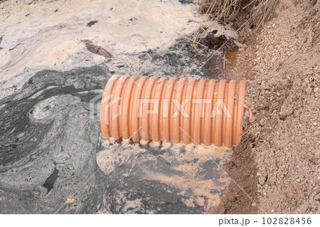 Drainage pipe with water stream flowing. Storm water management in public space, plastic pipe, rocks, and shrub plantings. Plastic pipes for the sewage system. Plumbing system underground Drainage pipe with water stream flowing. Storm water management in public space, plastic pipe, rocks, and shrub plantings. Plastic pipes for the sewage system. Plumbing system underground 102828456