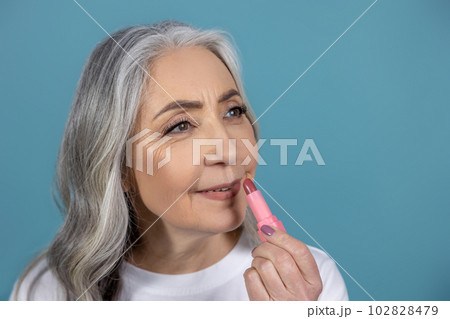 Beautiful aging woman with lipstick doing makeup 102828479