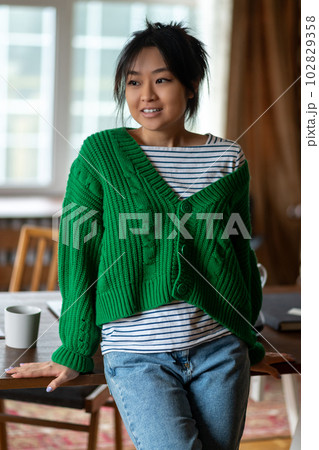 Asian girl in green shirt at home looking contented 102829358