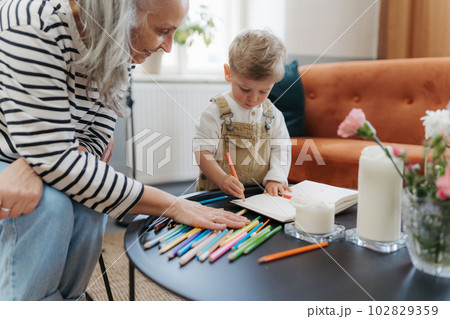 Grandson drawing in a notepad with his grandmother. Grandson drawing in a notepad with his grandmother. 102829359