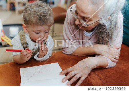 Grandson drawing in a notepad with his grandmother. 102829366