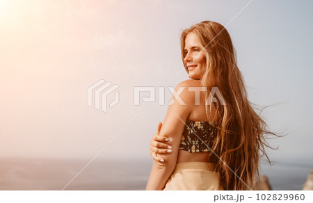 Woman travel sea. Happy tourist taking picture outdoors for memories. Woman traveler looks at the edge of the cliff on the sea bay of mountains, sharing travel adventure journey Woman travel sea. Happy tourist taking picture outdoors for memories. Woman traveler looks at the edge of the cliff on the sea bay of mountains, sharing travel adventure journey 102829960