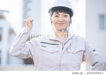 ガッツポーズのヘルメット姿のミドルの女性エンジニア 102830032