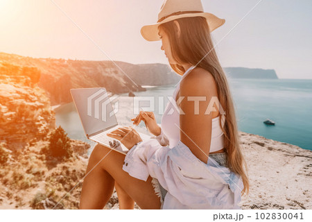 Woman sea laptop. Business woman in yellow hat freelancer with laptop working over blue sea beach. Girl relieves stress from work. Freelance, digital nomad, travel and holidays concept Woman sea laptop. Business woman in yellow hat freelancer with laptop working over blue sea beach. Girl relieves stress from work. Freelance, digital nomad, travel and holidays concept 102830041