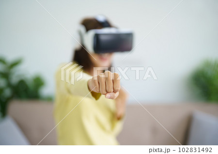 Young Asian woman gamer wearing virtual reality touching air during the VR experience Future home technology player hobby playful enjoyment concept. Young Asian woman gamer wearing virtual reality touching air during the VR experience Future home technology player hobby playful enjoyment concept. 102831492